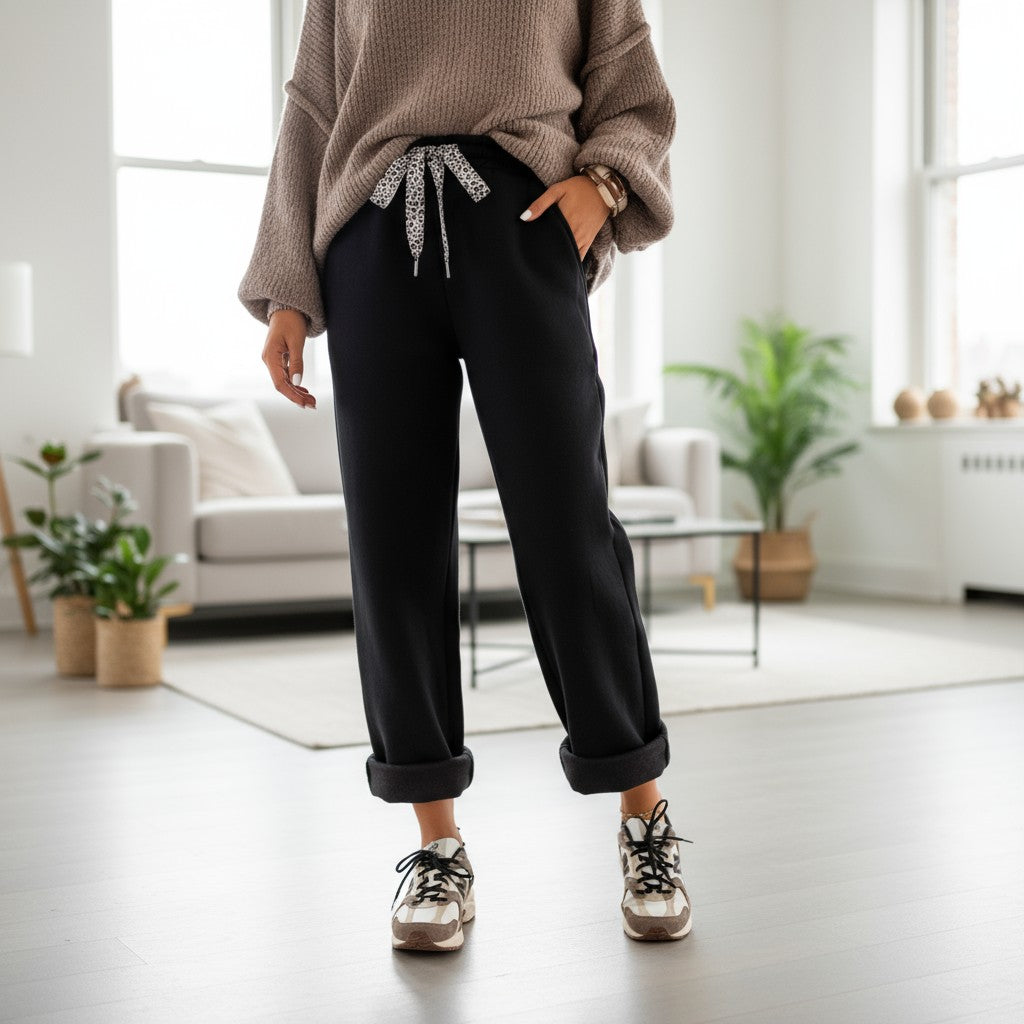 Model wearing COMFORT CULTURE PANTS (BLACK) with a cozy sweater and leopard drawstring, styled with casual sneakers.