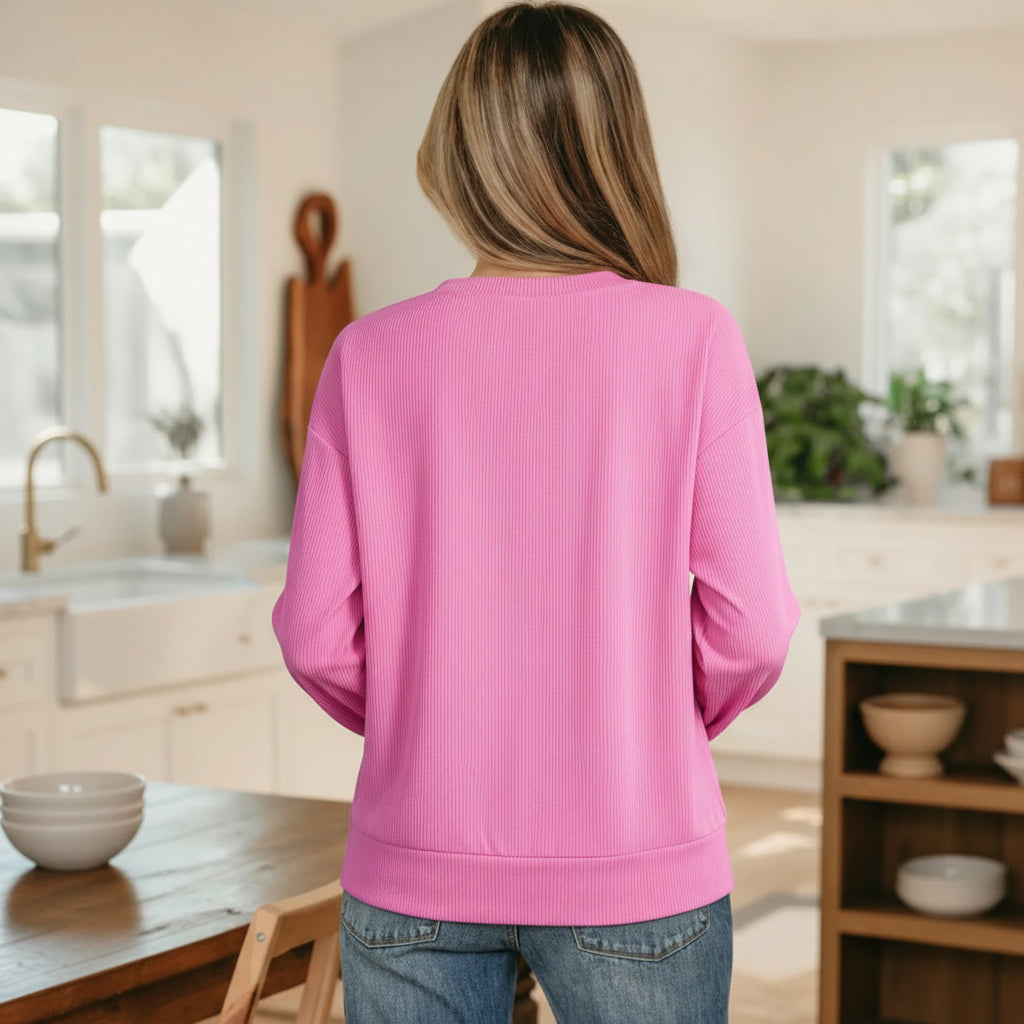 Back view of a woman wearing the SWEETIE PIE RIBBED TOP in pink, showcasing its ribbed texture and relaxed fit.