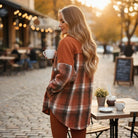 Model wearing HARVEST HAVEN JACKET in rust colorblock plaid, enjoying coffee outdoors in a cozy autumn setting.