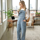 A woman enjoying coffee while wearing DENIM 4 DAYS OVERALLS - BIBI, highlighting a relaxed fit and casual style.