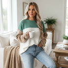 Model wearing MOUNTAIN AIR SWEATER in color block design with a cup, styled in cozy, modern living room.