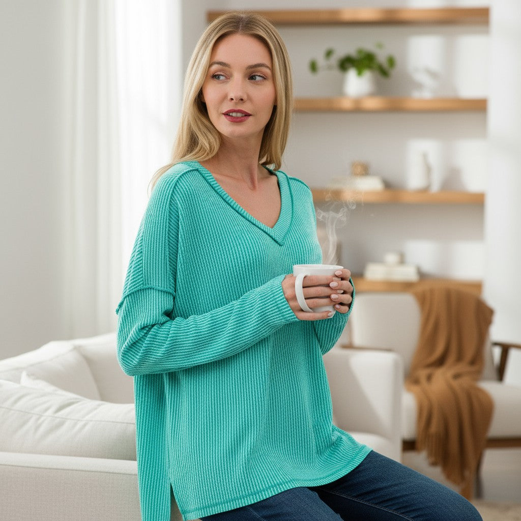Model wearing the COZY CONCEPTS RIBBED TOP (turquoise) while holding a coffee cup in a cozy setting.