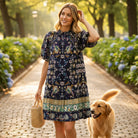 Woman wearing FINALLY MINE - UMGEE black floral mini dress walking with a dog on a sunny pathway.