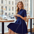 Model wearing the ROYAL LINES DRESS by She + Sky, a navy skater dress with a polo collar and contrast stitching.