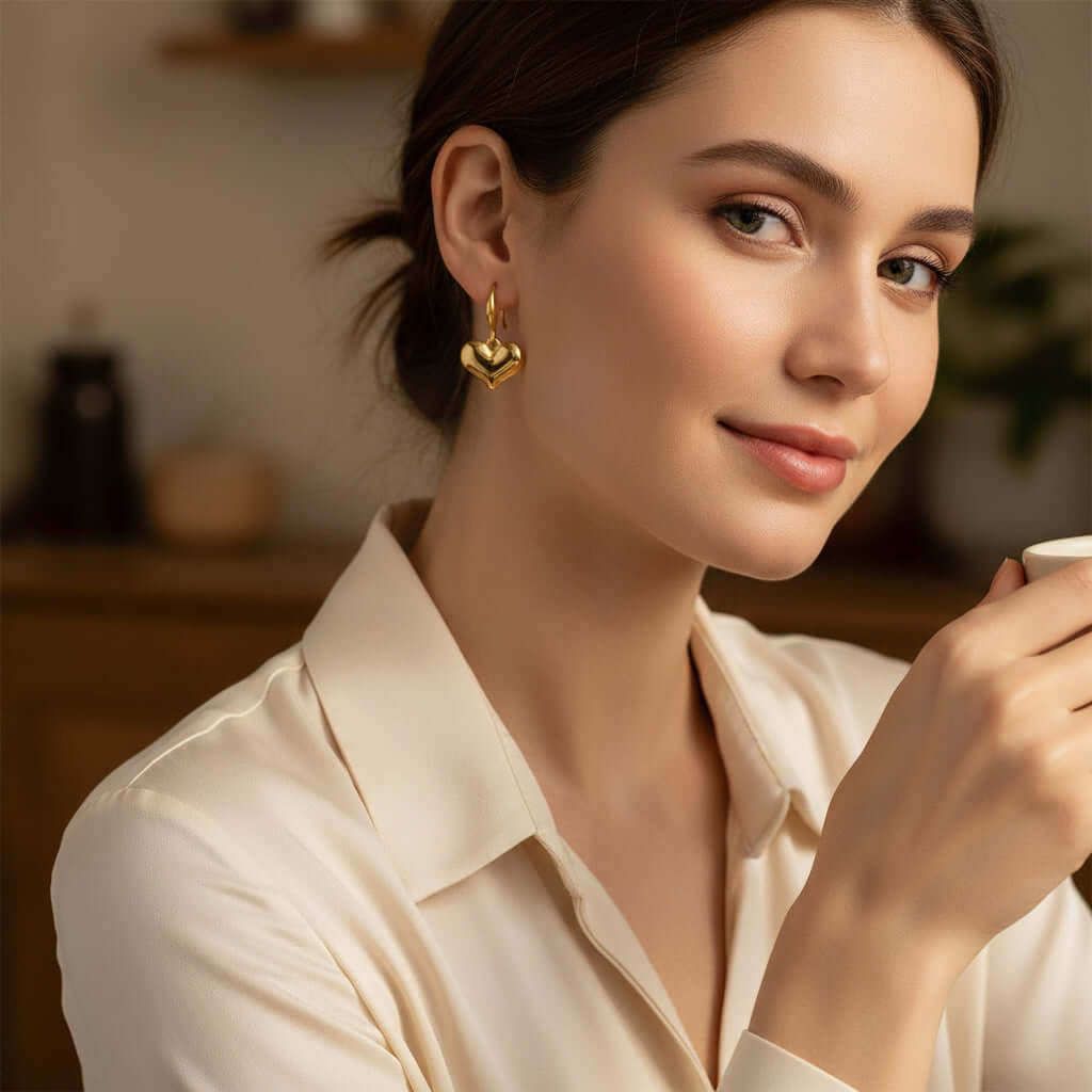 Woman wearing FOREVER YOURS EARRINGS, showcasing their heart shape and 18K gold-plated finish.