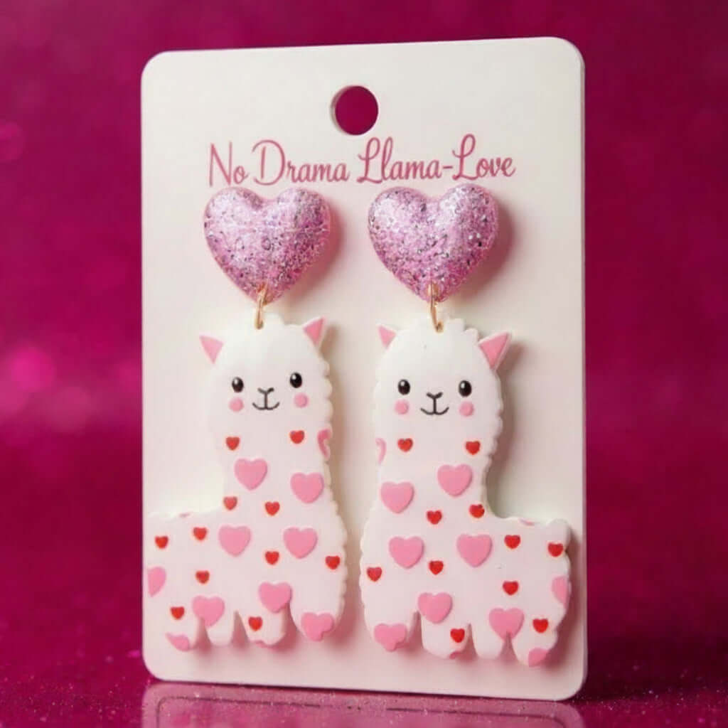 NO DRAMA LLAMA-LOVE EARRINGS with cute heart-covered llamas and pink heart studs on a display card.