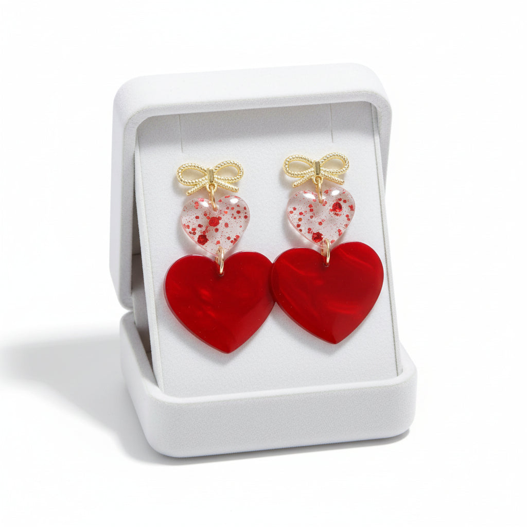 FOREVER YOURS EARRINGS featuring glossy red hearts and elegant gold-tone bow studs in a white box.