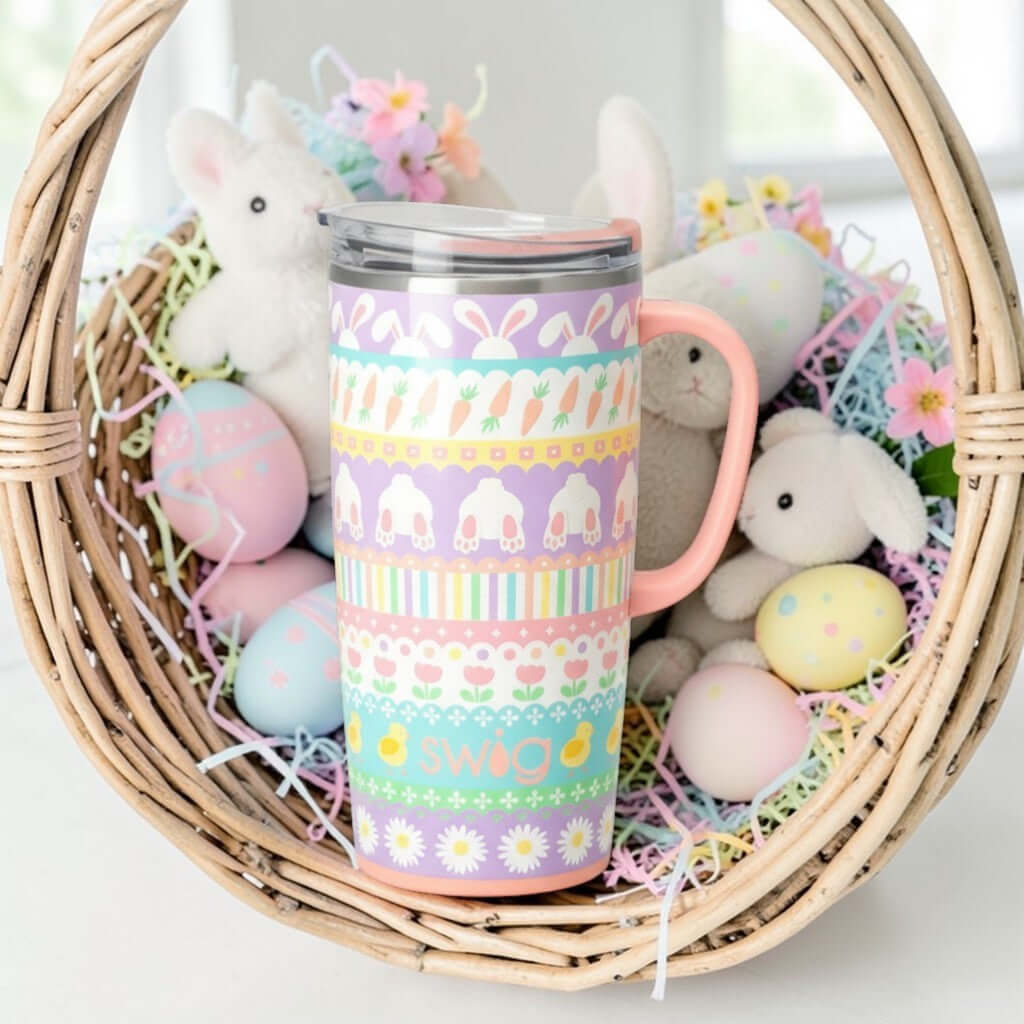 BUNNY TRAIL 22 OZ TRAVEL MUG - Swig Life in a basket surrounded by Easter eggs and plush bunnies.