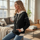 MODERN EDGE HOODIE worn by a woman enjoying coffee in a cozy living room, showcasing its stylish design and comfort.