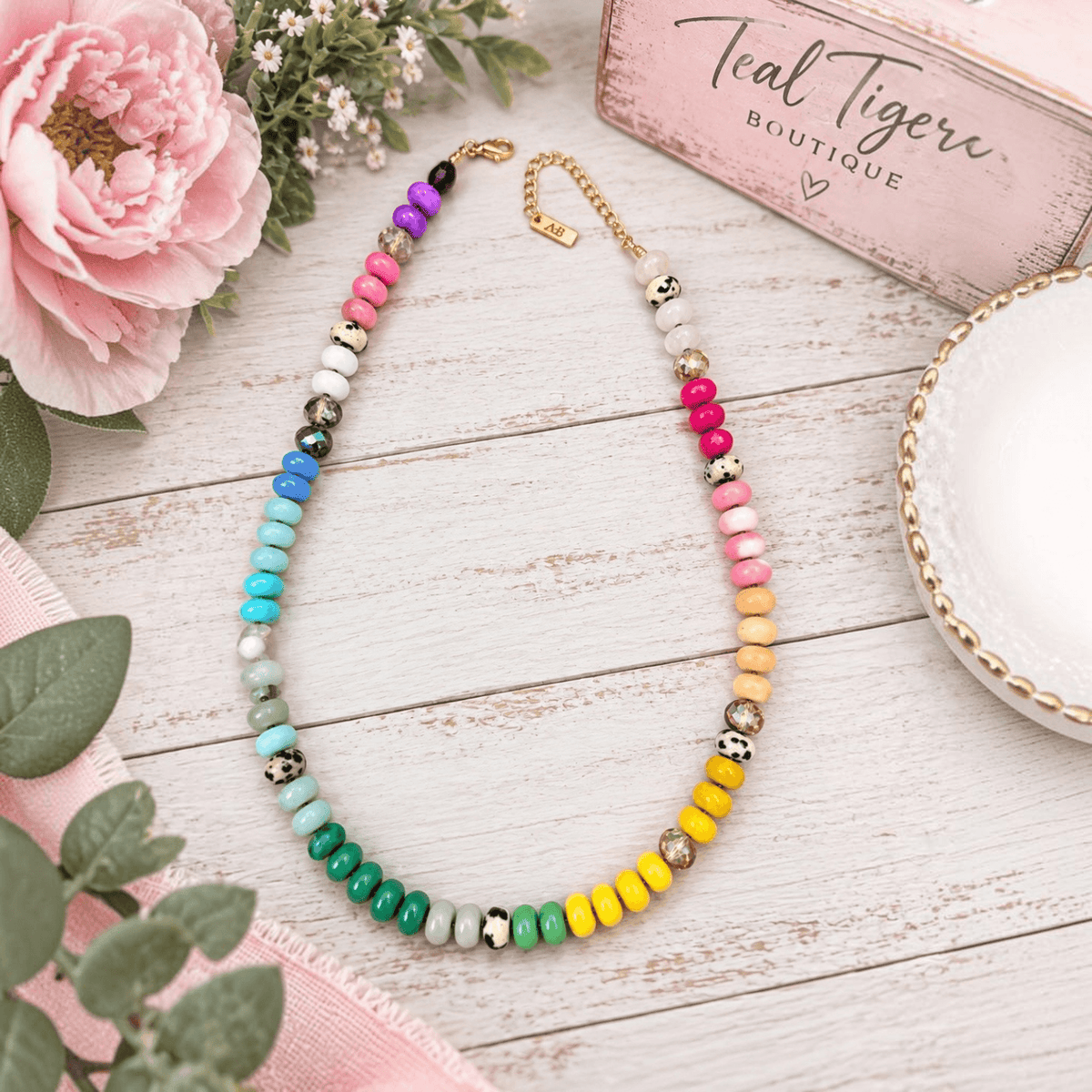 COLOR ME HAPPY NECKLACE with colorful beads, leopard-print accents, and gold-tone details on a rustic background.