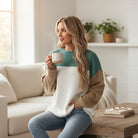 Model enjoying a warm drink while wearing the MOUNTAIN AIR SWEATER in a cozy living room setting.