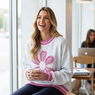 DAYDREAM BELIEVER - Sage + Fig (gray) oversized pullover with daisy design, showcased by a smiling model in a cozy café.