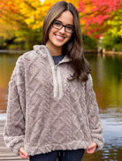 Woman wearing charcoal Teddy Bear Sherpa fleece pullover with cable pattern by a lake with autumn trees in the background.