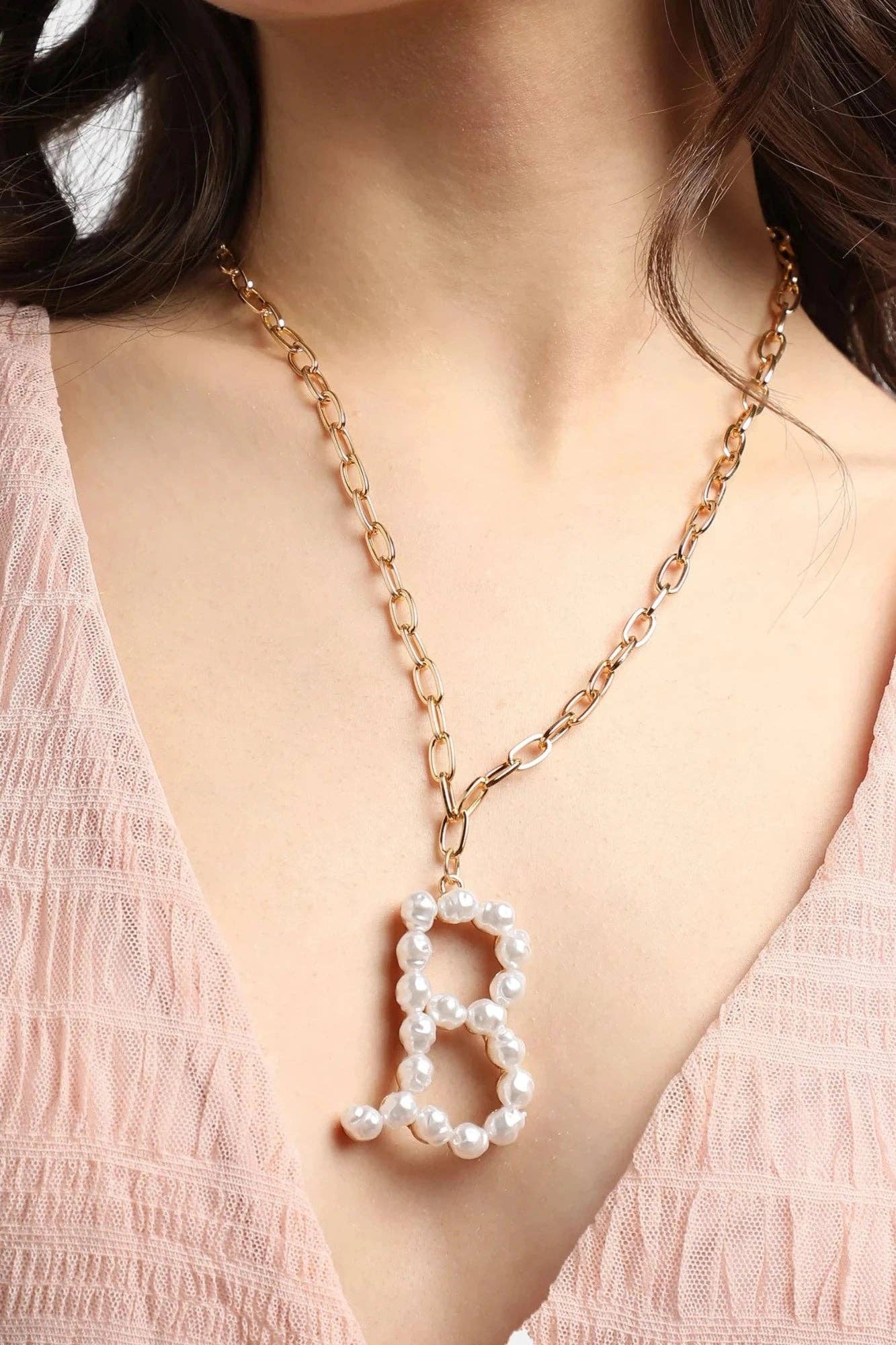 Woman wearing Pearl Essence Monogram Necklace with freshwater pearls and gold-tone chain by Avenue Zoe.