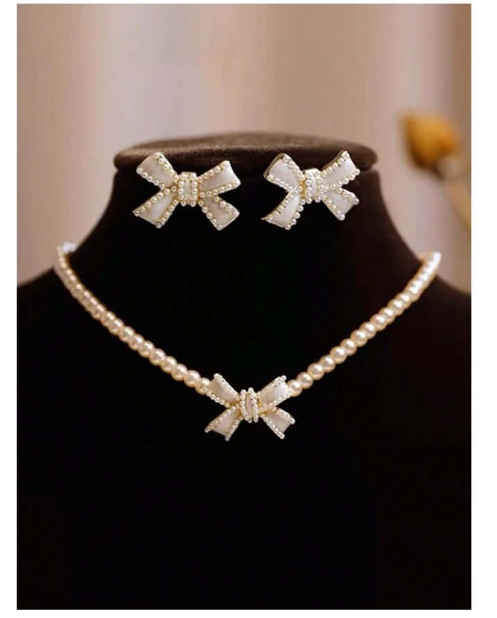Elegant bow necklace and earrings set with faux mother of pearl and pearls, perfect for any occasion.