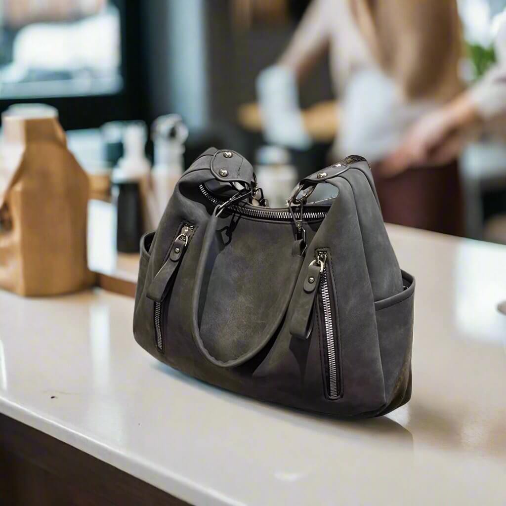 Stylish CHRISTINA Shoulder Bag in faux suede, with zippers and spacious compartments, on a countertop for everyday use.