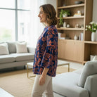 TIMELESS CHARM - Umgee (blue) top displayed by a smiling woman in a stylish living room setting.