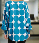 Woman wearing Blue Abyss blouse by Jodifl with ocean blue octagon dots, V-neck, smocked cuffs, oversized fit, back view.