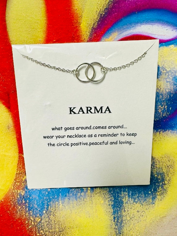 Silver toned necklace featuring intertwined rings and a card with uplifting "Karma" quote.