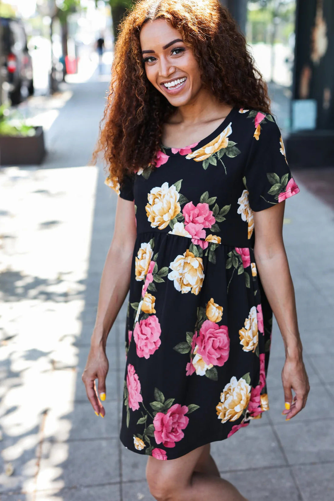 Model in floral Twilight Garden Party Dress, featuring bright blooms on a black background, perfect for summer outings.