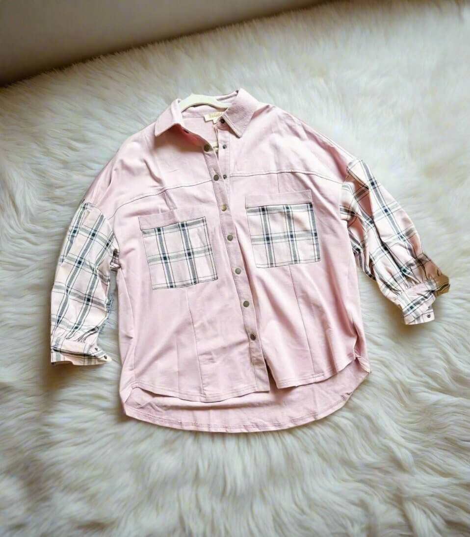 Light pink FAST FORWARD Top by Listicle with plaid sleeves, pockets, and snap front, displayed on a soft furry surface.