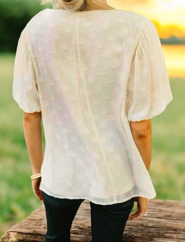 Back view of cream Pointed Conversations Top by Umgee with short bubble sleeves and subtle polka dots.