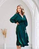 Luxurious dark green midi dress with smocked sleeves, styled elegantly in an arched doorway.