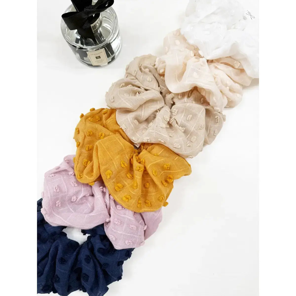 CLOUD COMFORT SCUNCHIE assortment, featuring pompom texture in six stylish colors for a cozy hair accessory.