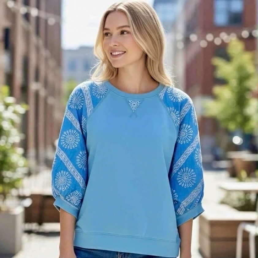 AZURE AVENUE TOP- - Umgee model wearing a stylish blue top with patterned 3/4 sleeves outdoors.