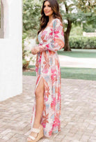 Model in TROPICAL SENSATION DRESS with high slit and floral pattern, perfect for summer events.