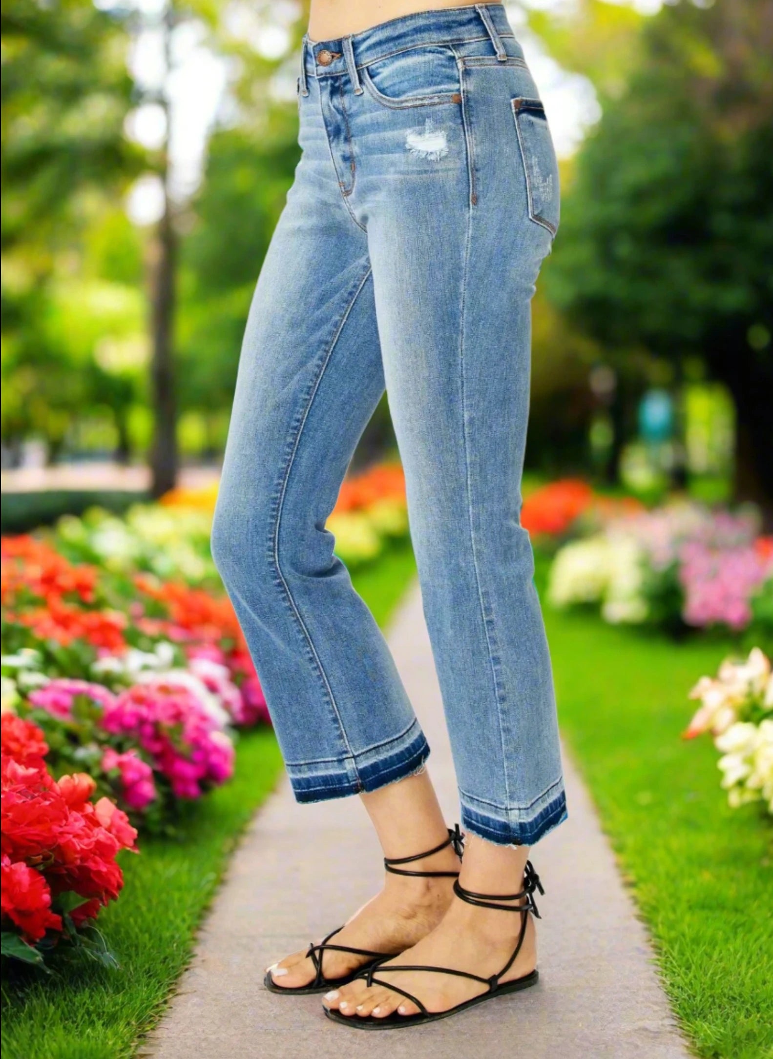 Cropped bootcut Judy Blue Amelia Jeans with a stretchy fit, styled with sandals in a vibrant garden setting.