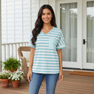 Model wearing UNSTOPPABLE YOU TOP (aqua) in blue stripes, showcasing casual style and comfort on a porch.