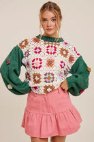 Woman wearing SQUARE UP SWEATER with boho floral patchwork and 3D crocheted flowers, styled with a pink skirt.