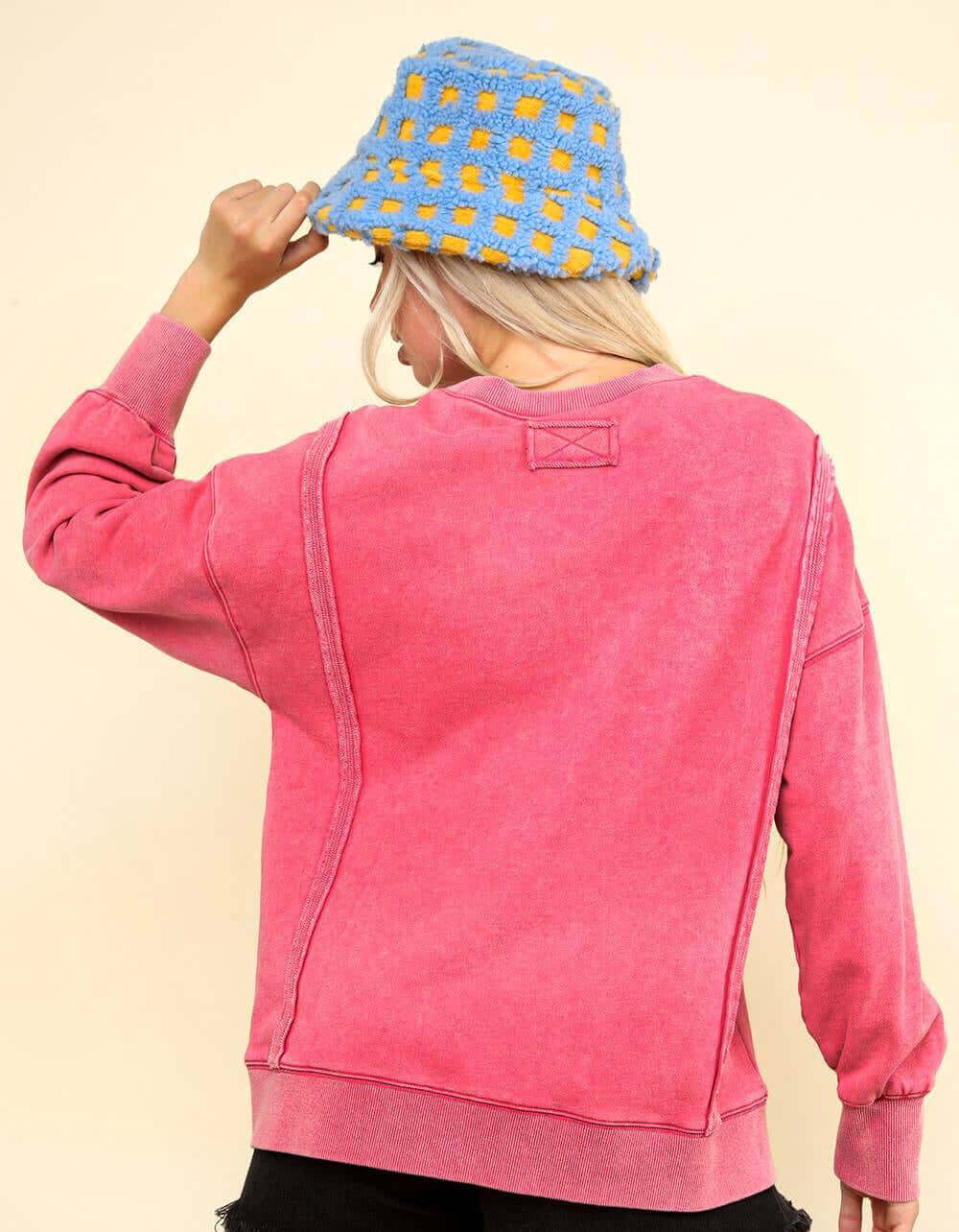 Woman wearing an oversized pink Flex Time Crew Neck with stylish stitch details and a blue crochet bucket hat.