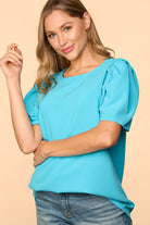 Woman wearing the Blue Haven Top by Haptics, a stylish aqua blouse with bubble puff sleeves.