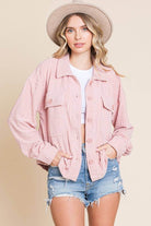 Lightweight women's pink embossed shacket with dolman sleeves and flap pockets, styled with a hat and shorts.