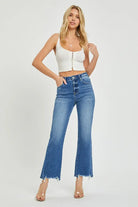 Model showcasing Risen Nora Jeans in a medium dark wash with frayed hem and high rise, paired with a white crop top.