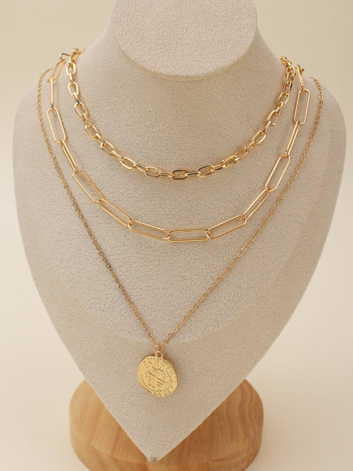 Gold multi-layer chain necklace set with pendant displayed on a jewelry stand, featuring elegant and delicate design.