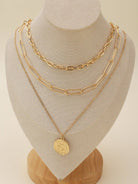 Gold multi-layer chain necklace set with pendant displayed on a jewelry stand, featuring elegant and delicate design.