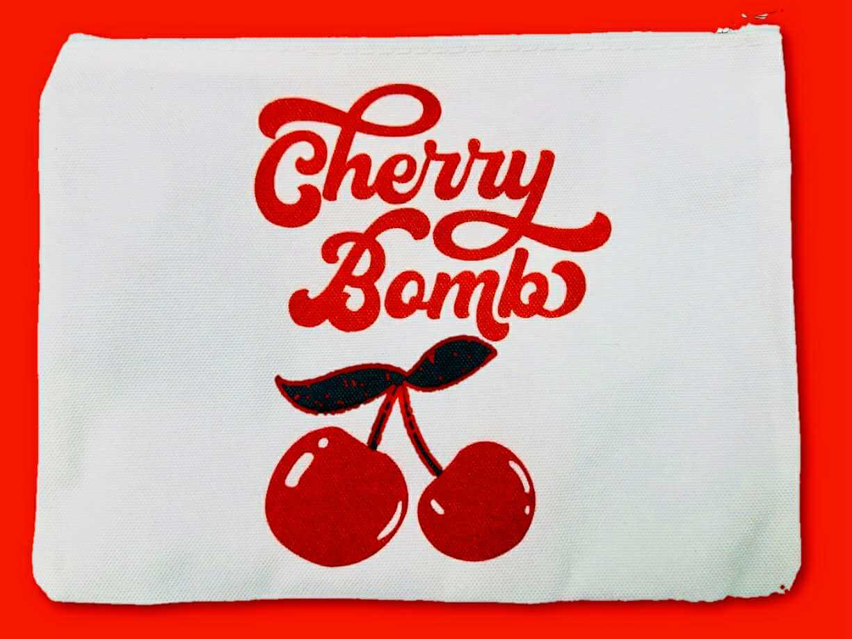 Cherry Bomb cosmetic bag featuring retro script and cherries on a white nylon pouch, stylish and durable.