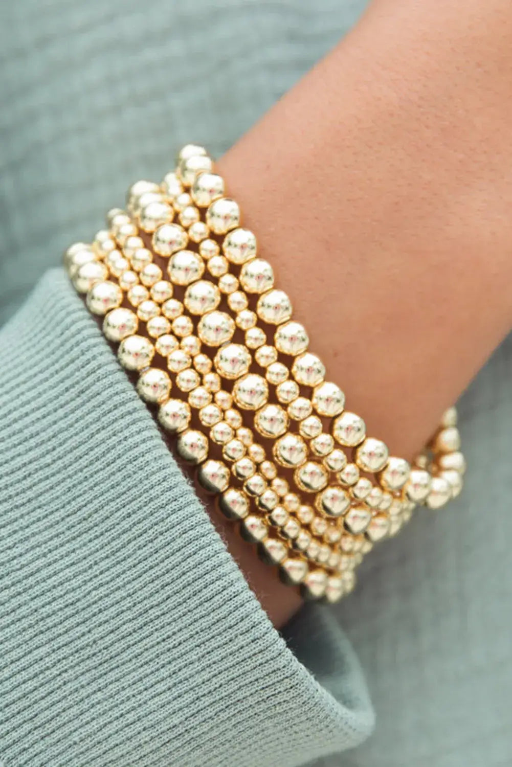 Gold tone minimalist beaded bracelet set worn on wrist, showcasing a chic and elegant style.