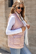 REVERSIBLE RETREAT VEST! Model wearing a pink sherpa lined quilted reversible vest with sunglasses.