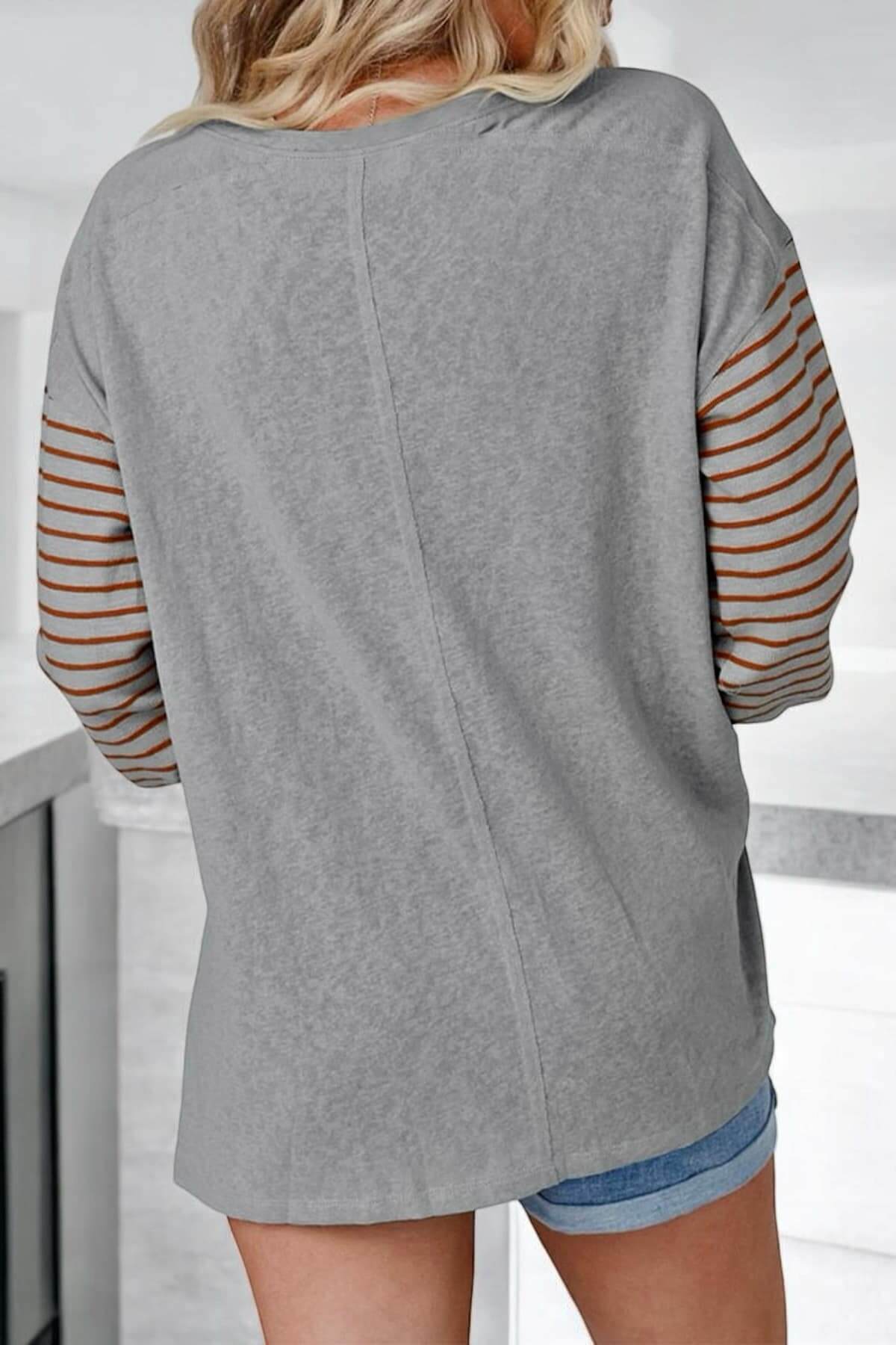 Woman wearing a block party top with smoke gray and rust striped sleeves, showcasing a stylish oversized design.