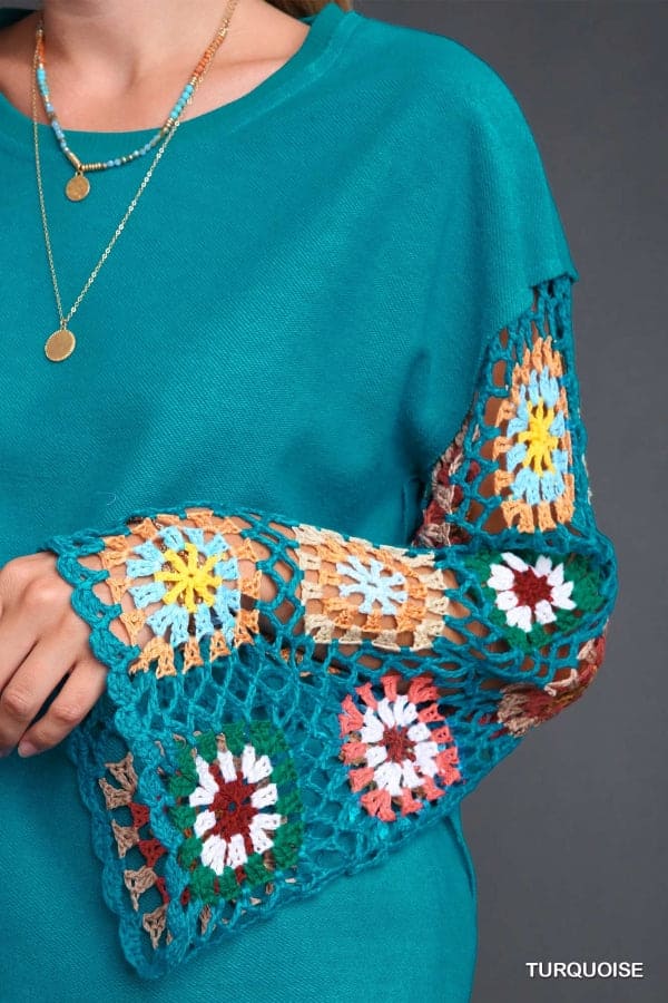 Turquoise crochet sleeve top with colorful hand-knit details and a round neck, showcasing intricate floral patterns.