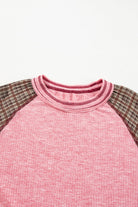 Mixed Blessings Top with ribbed fabric and plaid patchwork sleeves in pink and gray, showcasing a cozy and chic raglan design.