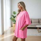 Woman wearing a pink Casual Escape Romper, showcasing its relaxed fit and casual style in a bright interior.