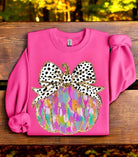 Magenta pumpkin art crewneck on a wooden bench, featuring a vibrant applique with a bow design. Perfect for cozy autumn styling.