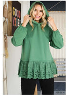 Woman wearing a green ADVENTURE AWAITS hoodie top with ruffle hem by Cotton Bleu, featuring long sleeves and cozy oversized fit.