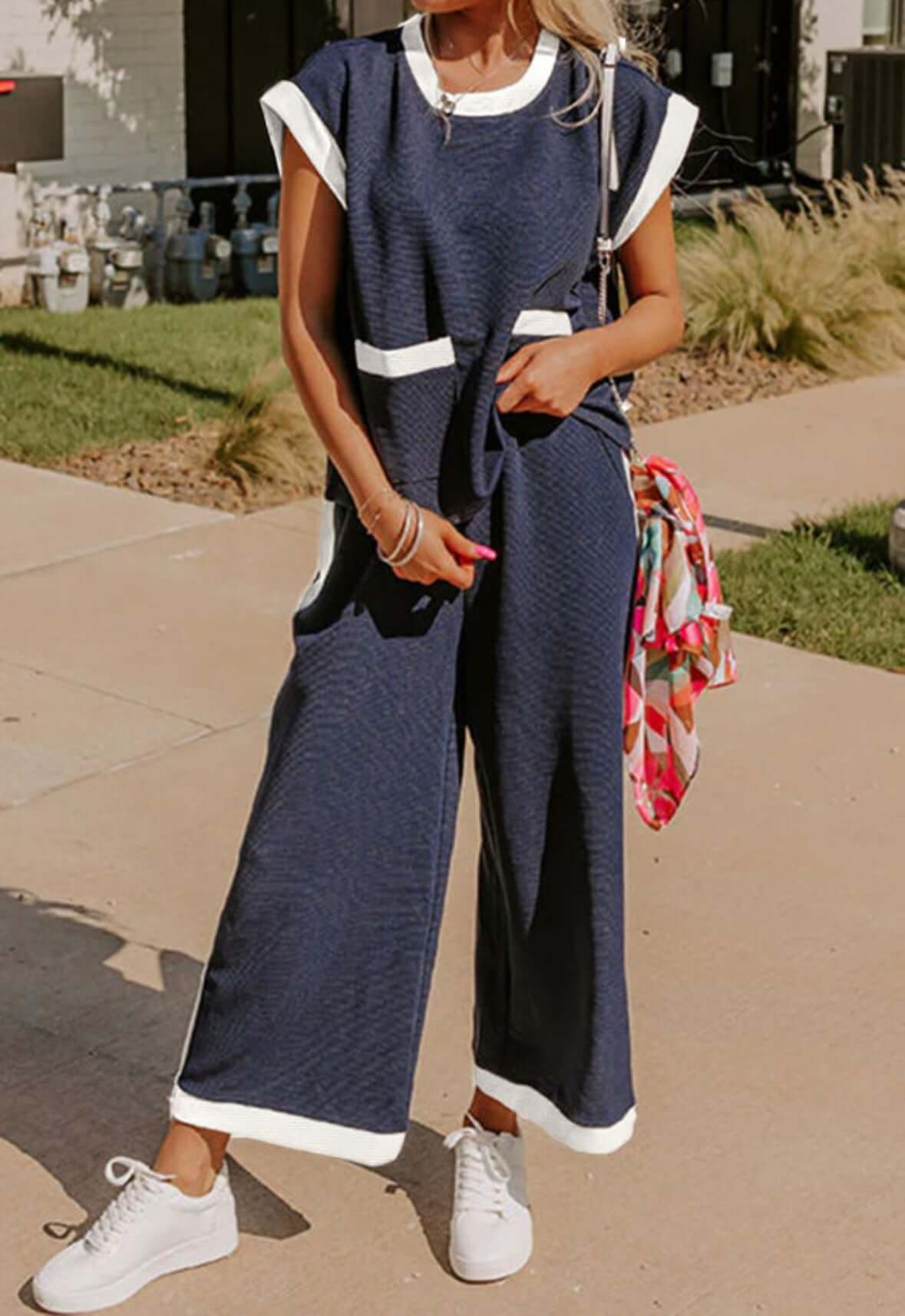 Model wearing the Harbor View two-piece navy pants set with white trim and front pockets, showcasing a coastal chic style.