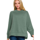 Woman modeling the TRANQUIL TRAILS PULLOVER in soft green, featuring a relaxed fit and cozy design.